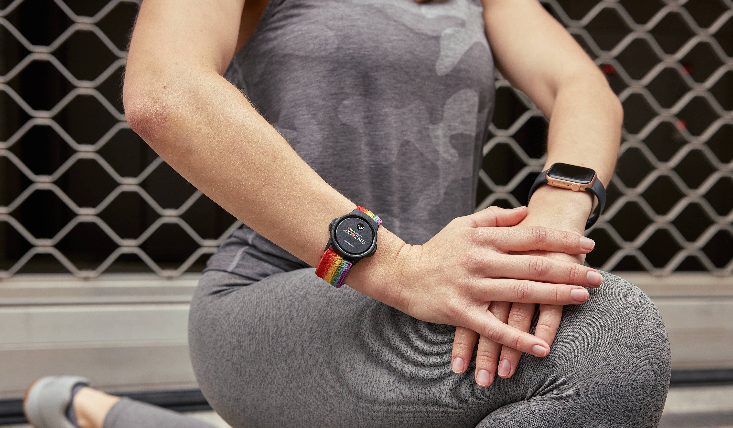 User exercising with MZ-Switch worn on wrist with pride strap, grey leggings and top